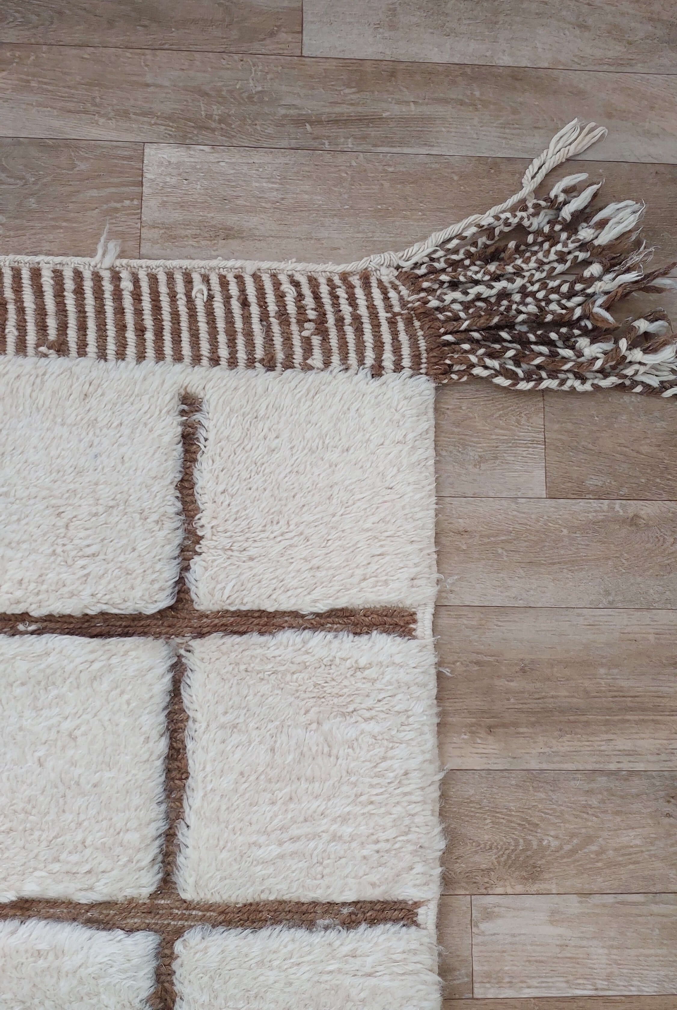 Custom Moroccan rug in white and brown hues placed on a wooden floor