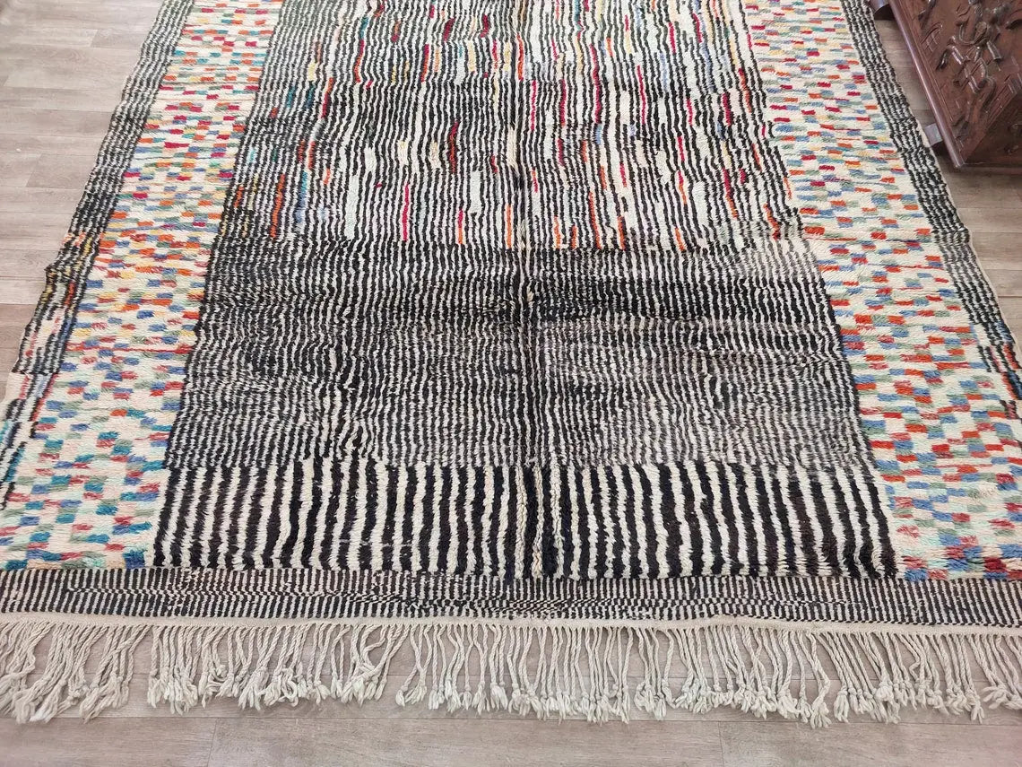 Multicolored Moroccan woven rug with fringe on a wooden floor