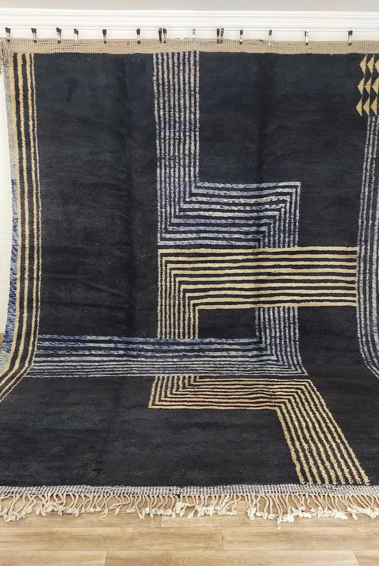 Black and gold geometric patterned Moroccan rug on a wooden floor