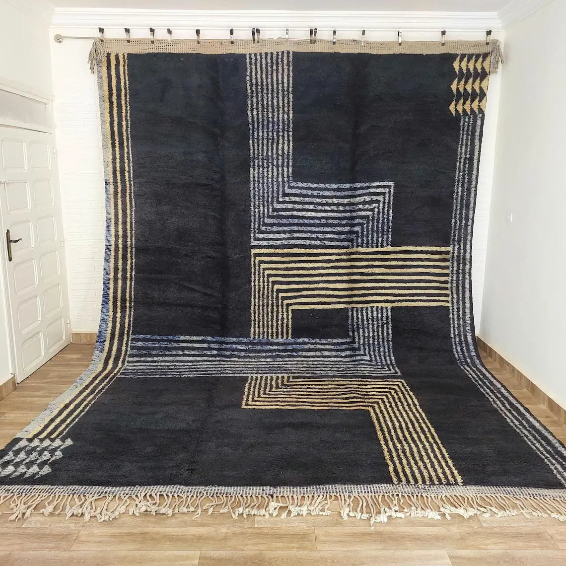 Black and gold geometric patterned Moroccan rug on a wooden floor