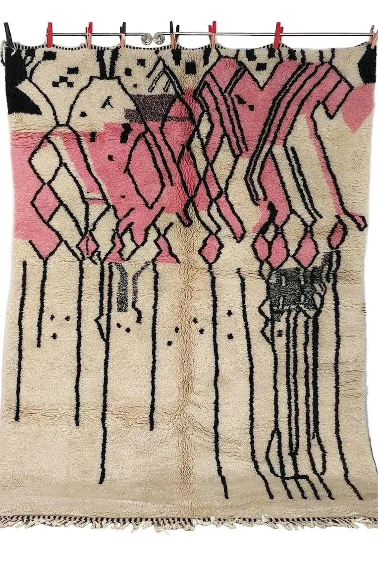 Decorative beni mrirt rug with pink and black patterns hanging on a line indoors.