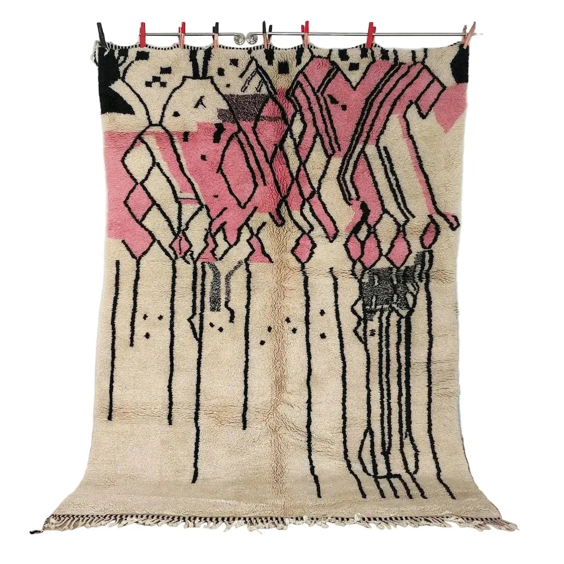 Decorative beni mrirt rug with pink and black patterns hanging on a line indoors.