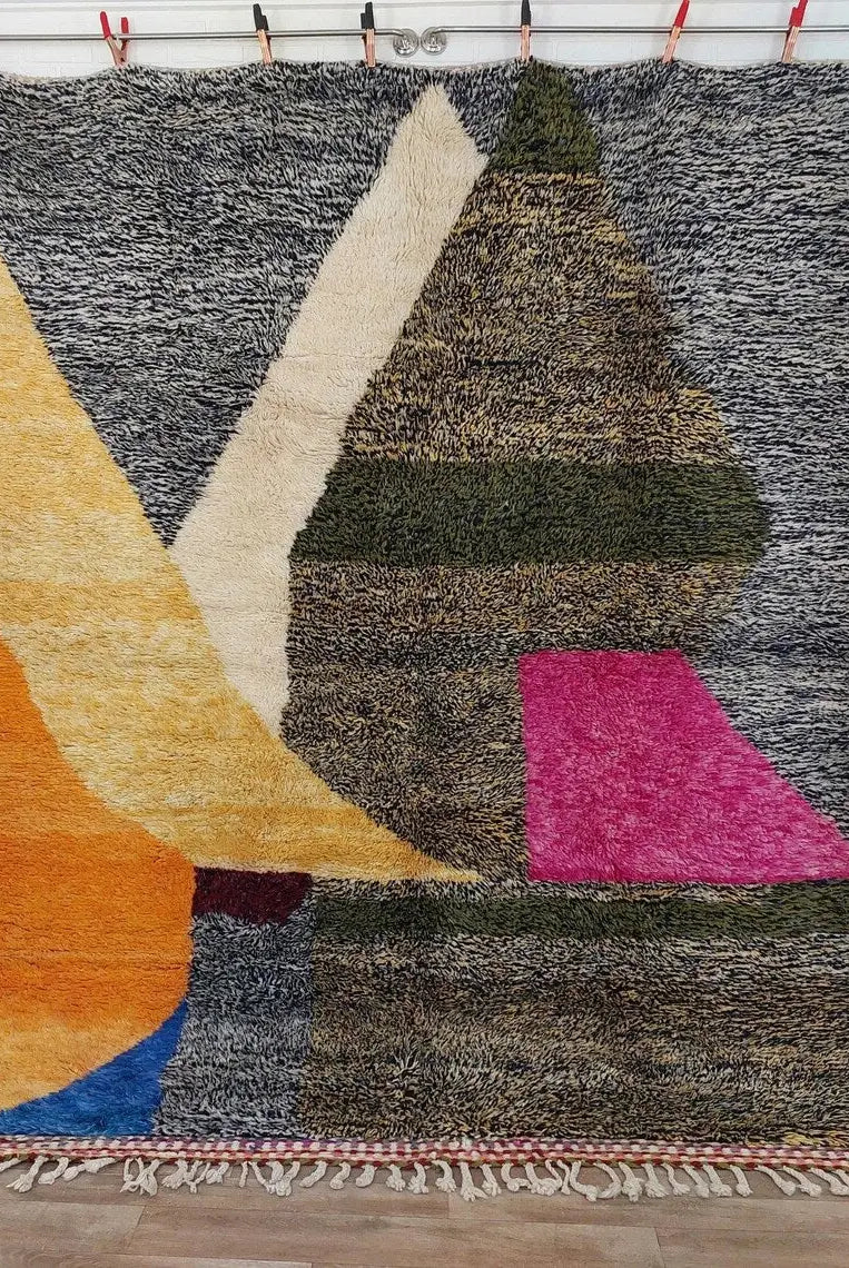 Multicolored textured rug with geometric patterns on a wooden floor.
