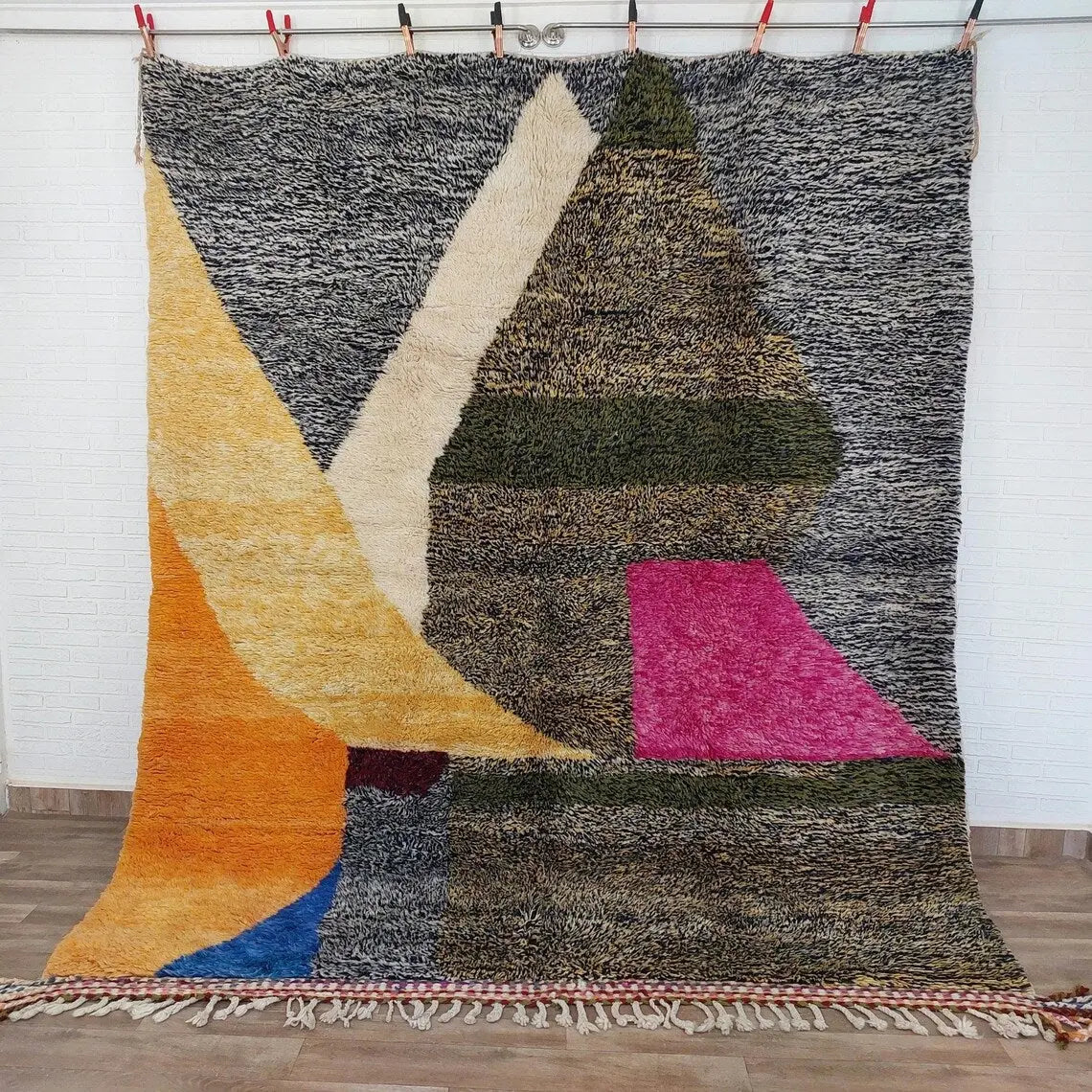Multicolored textured rug with geometric patterns on a wooden floor.