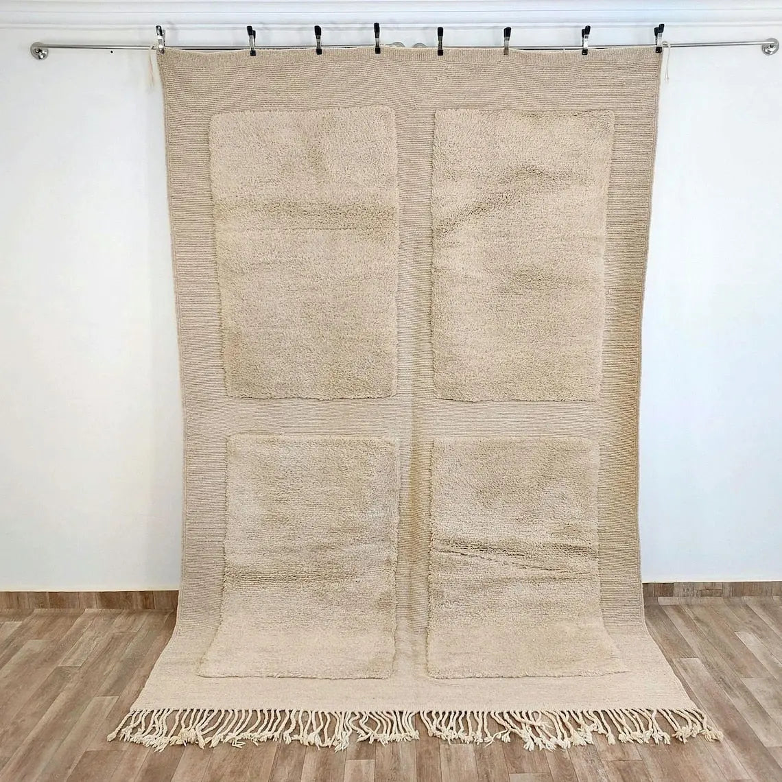 Beni mrirt Beige woven rug with four square patterns and fringe on a wooden floor.
