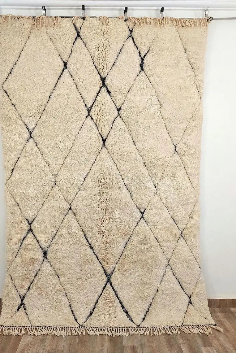 Beni mrirt Beige and black diamond patterned rug on a wooden floor with white walls.
