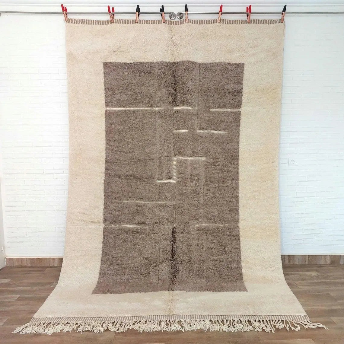 Moroccan beni mrirt rug with geometric pattern draped over a surface, possibly a bed or chair, against a white wall.