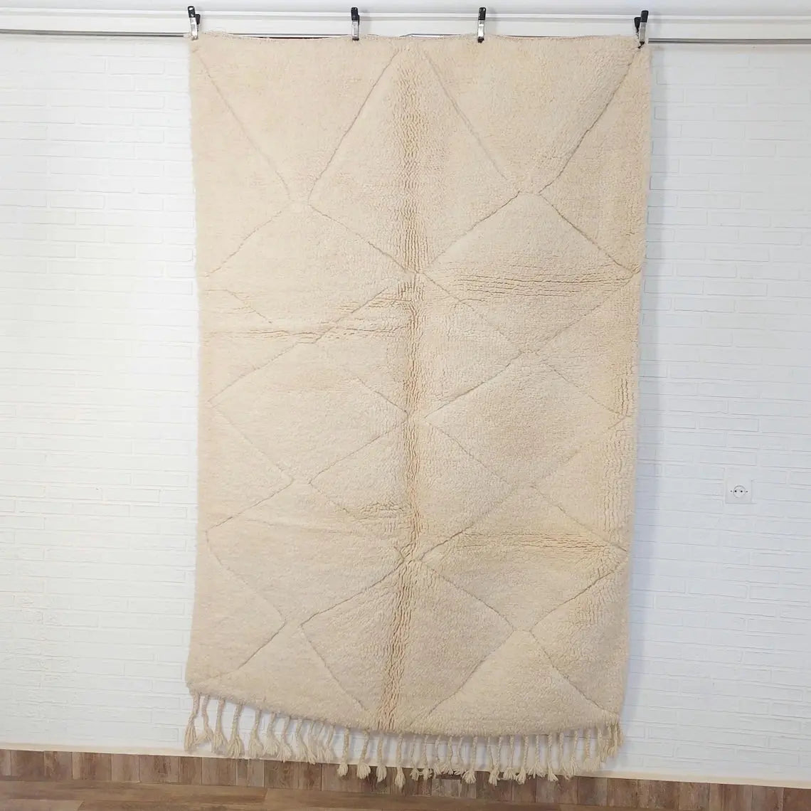 Beige quilted throw blanket with fringe on a white background