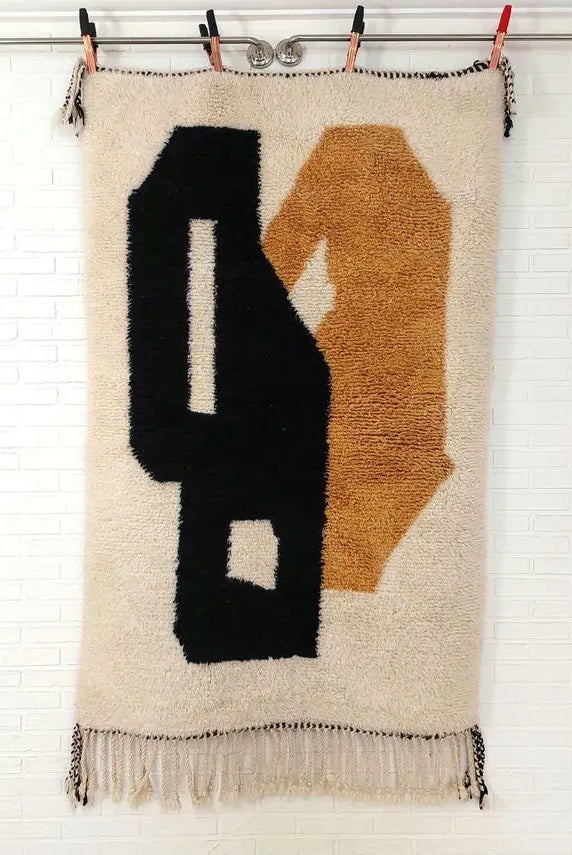 Textile art piece with black and brown abstract shapes on a white background