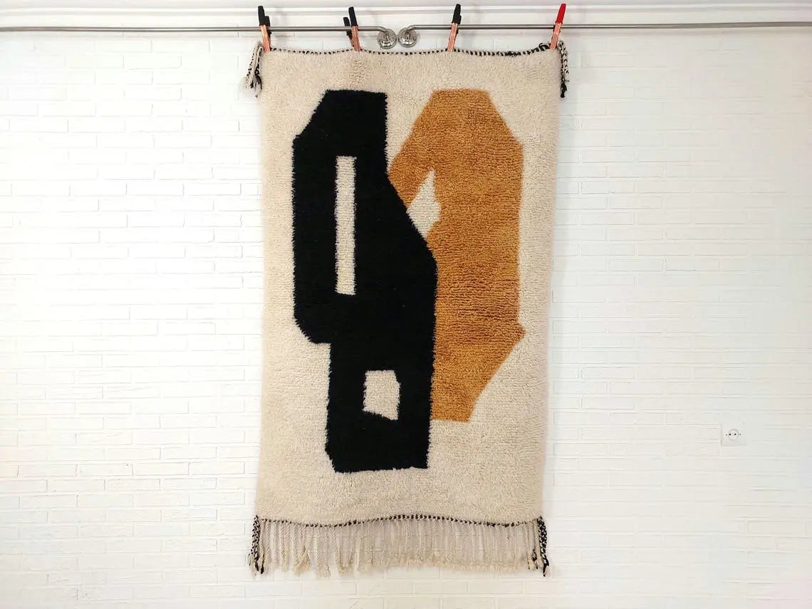 Textile art piece with black and brown abstract shapes on a white background