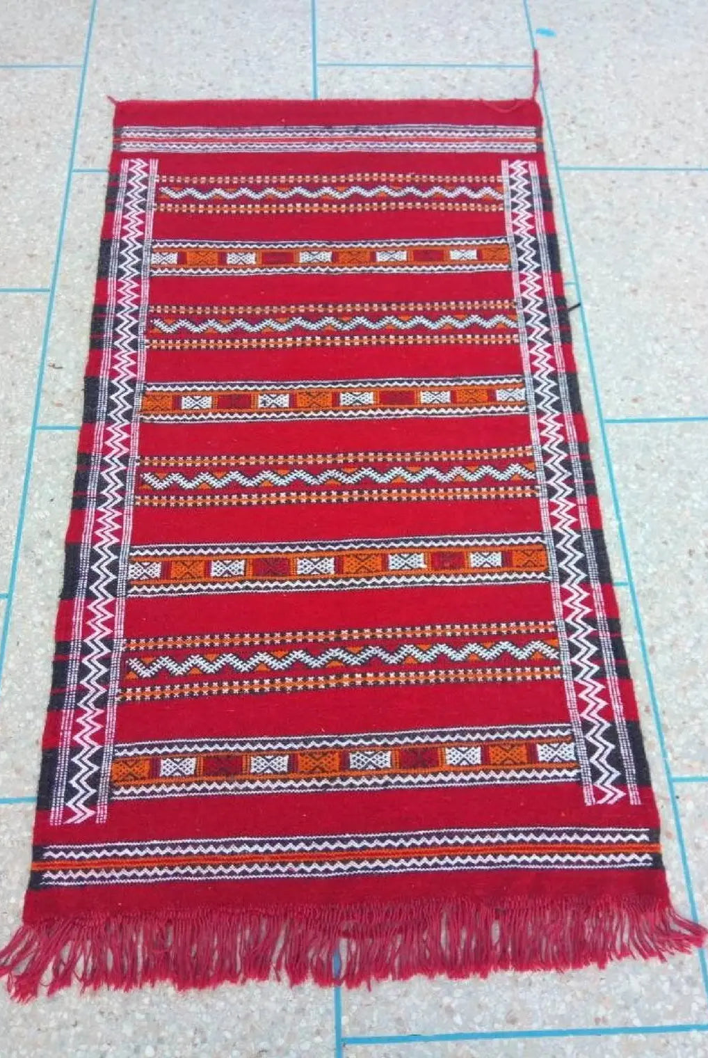 Red woven textile with pattern on a grid background