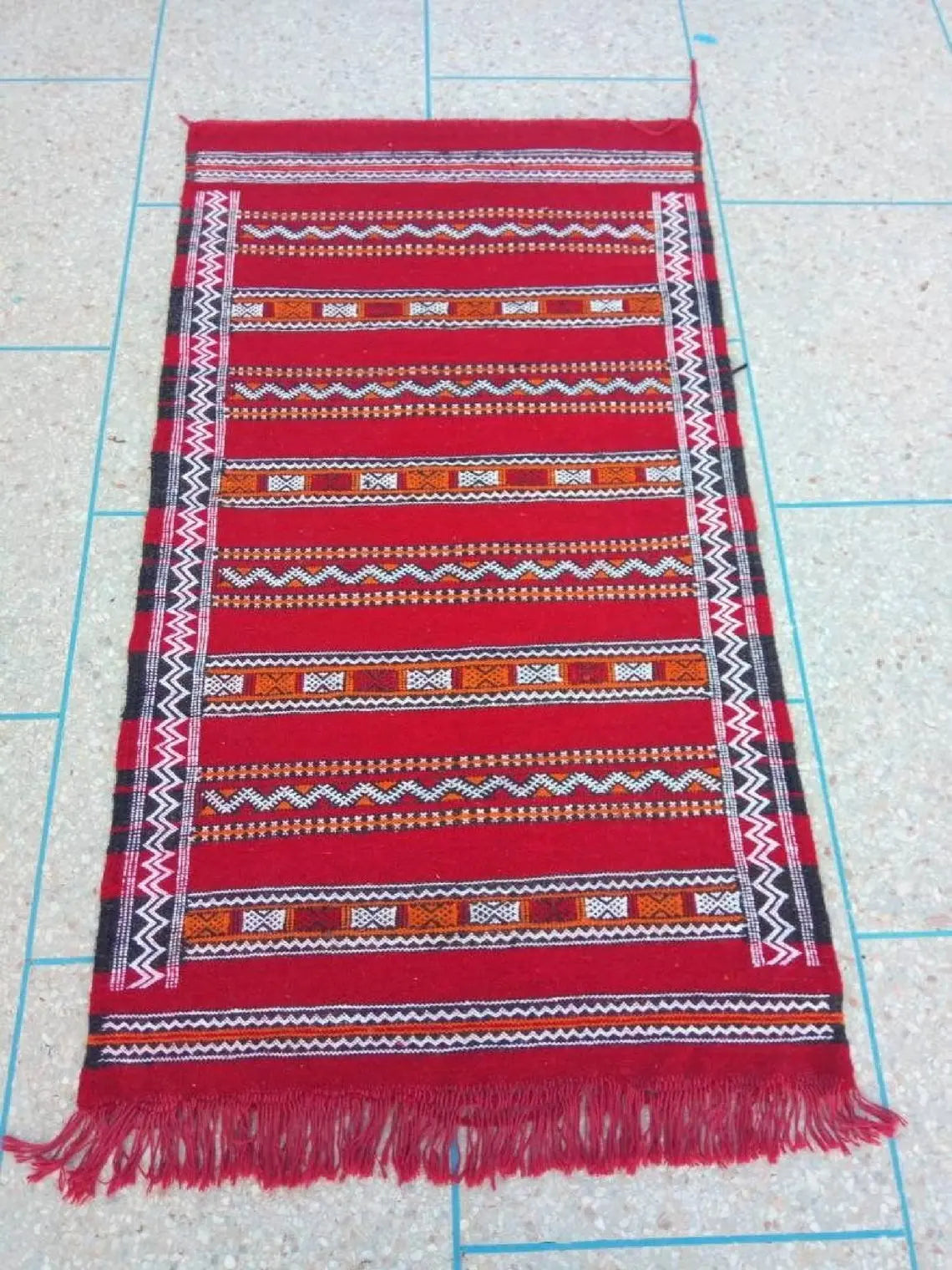 Red woven textile with pattern on a grid background