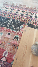 Load image into Gallery viewer, Masterpiece Moroccan rug displayed on a wooden table with a decorative vase