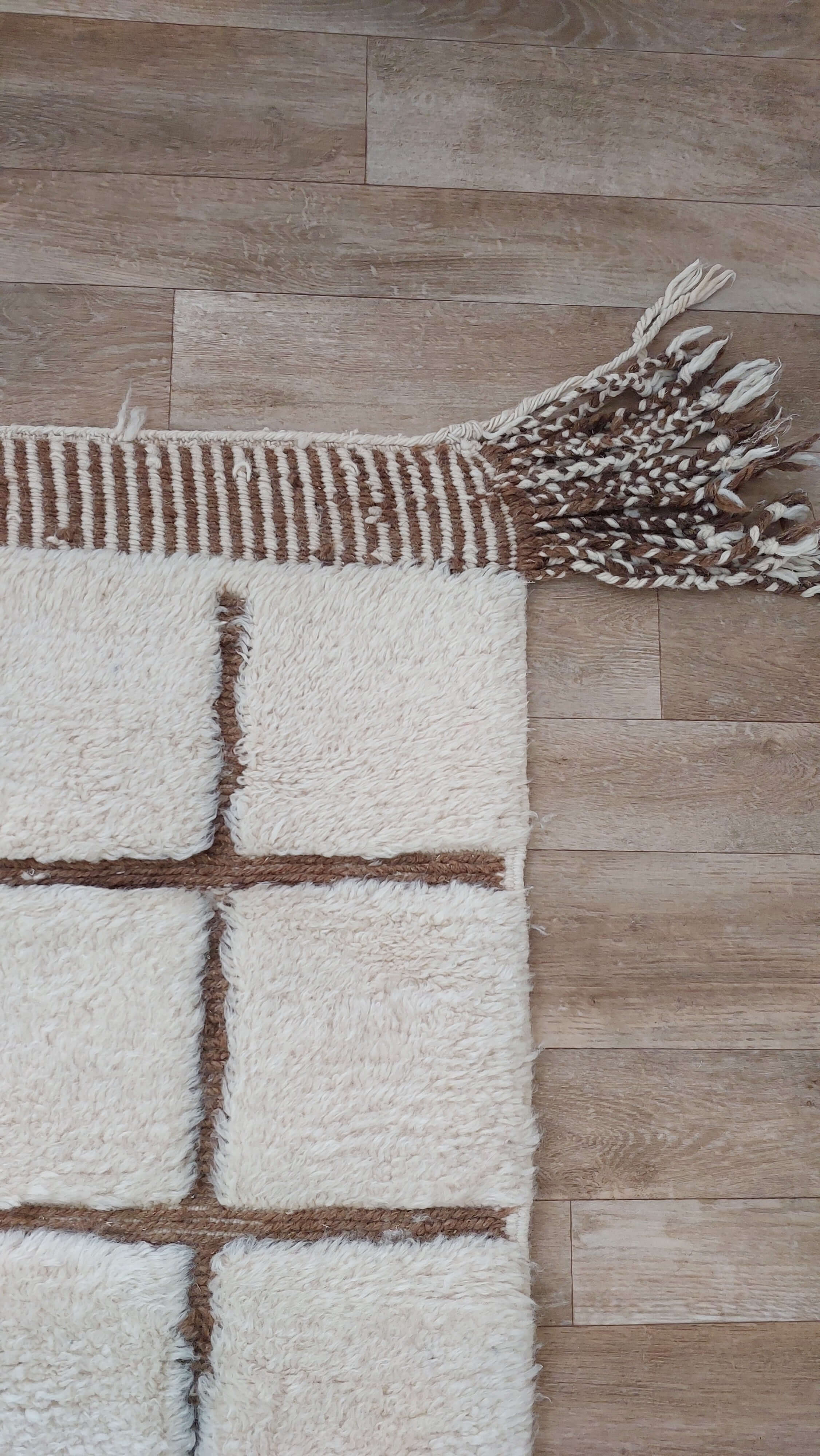Custom Moroccan rug in white and brown hues placed on a wooden floor