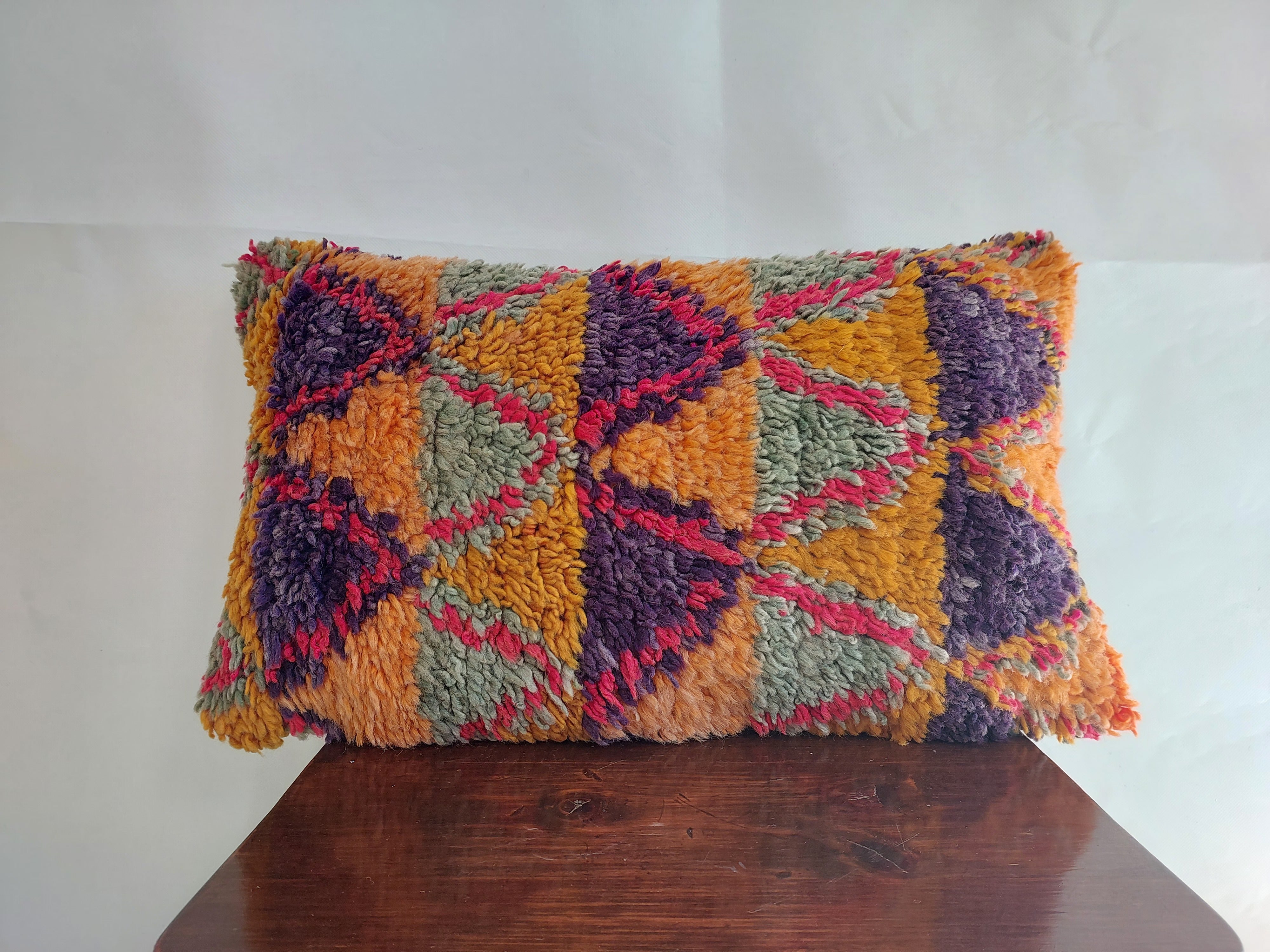 Colorful textured pillow on a wooden surface with a white background
